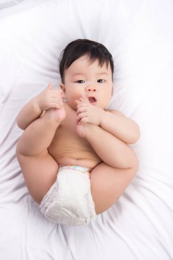Beyaz yatakta ağzına ayak ayakları portre sevimli küçük Asya çocuk 6 aylık 