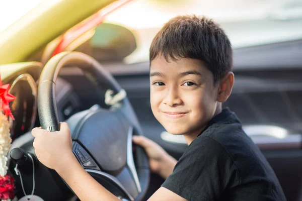 Kleine jongen zittend voor het stuur van de auto — Stockfoto