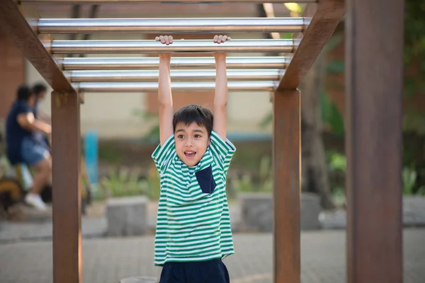 Menino pendurado no bar no parque infantil — Fotografia de Stock