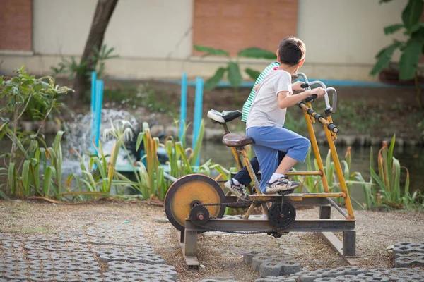 Menino equitação poder ginásio bicicleta no parque infantil — Fotografia de Stock