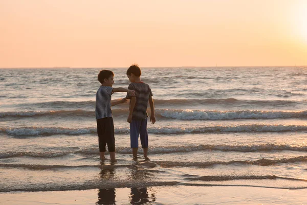 Petit garçon jouant au coucher du soleil sur la plage — Photo