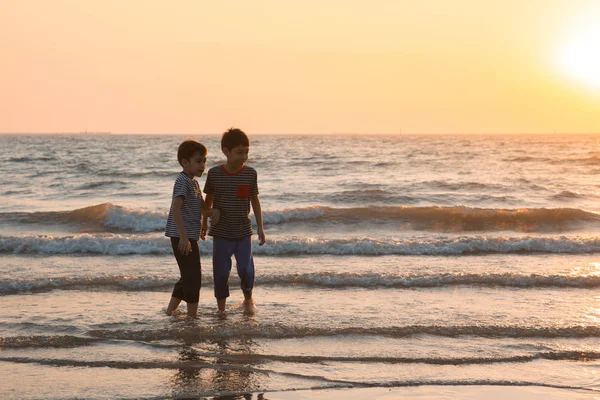 Petit garçon jouant au coucher du soleil sur la plage — Photo