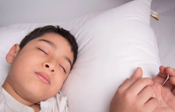 Маленький хлопчик спить у ліжку з білою кришкою ковдри — стокове фото