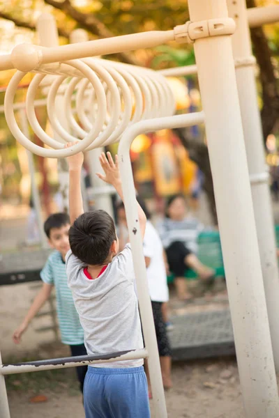 Little boy hanging on the bar at the playground — Stock Photo, Image