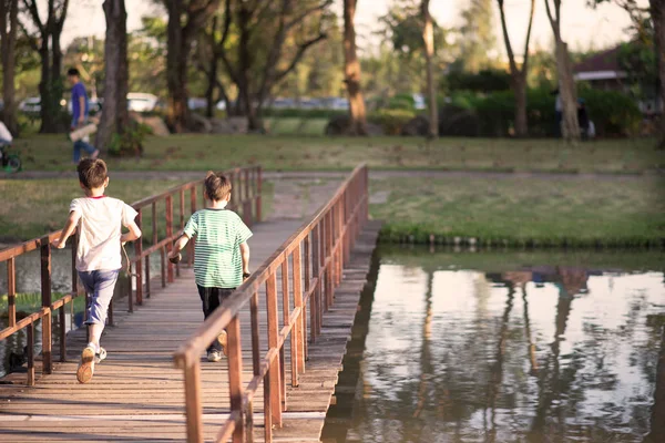 Liten pojke gå över bron i parken — Stockfoto