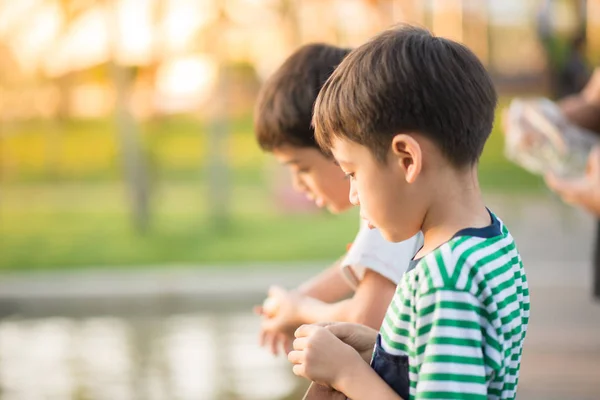 Close up face of little boy feeding fish in the park — Stock Photo, Image