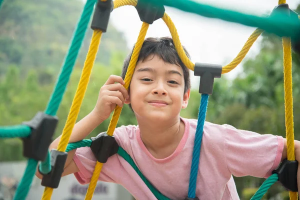 Kleiner Junge klettert Seil auf Spielplatz — Stockfoto