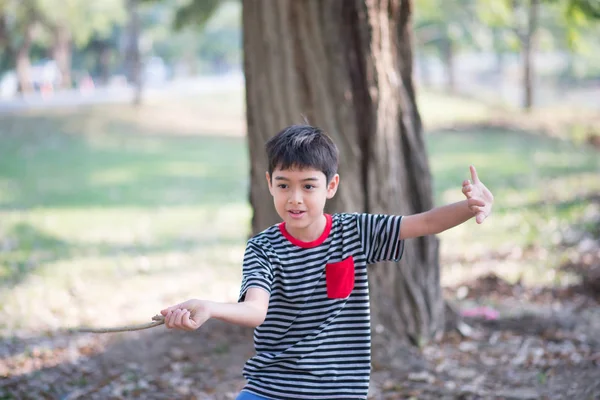 Kleiner Junge spielt im Sommer mit großem Laub im Park — Stockfoto