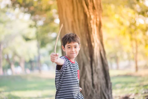 Liten pojke leker med stora lämna sommartid park utomhus — Stockfoto