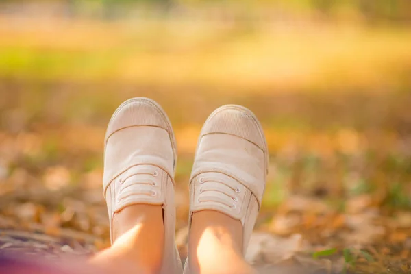 Close-up van vrouw sneaker schoenen in het park zitten terwijl u ontspant — Stockfoto