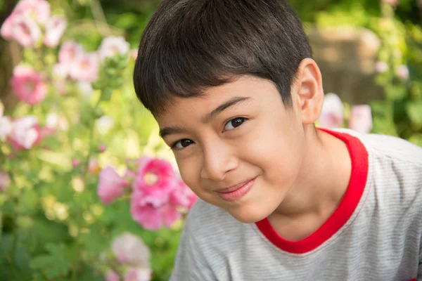 Chłopiec wącha kwiat w parku — Zdjęcie stockowe