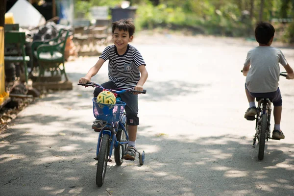 Mladšímu sourozenci chlapce jízdní kolo společně v parku — Stock fotografie