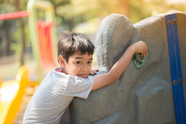 Liten pojke klättring på klippor väggen vid lekplats — Stockfoto
