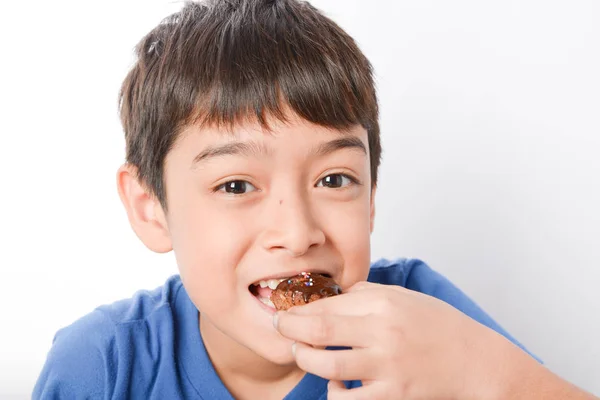 Мальчик готовит и ест шоколадный торт дома — стоковое фото