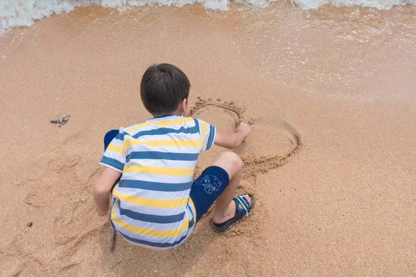 Jongetje tekening zand door hand hart vorm — Stockfoto