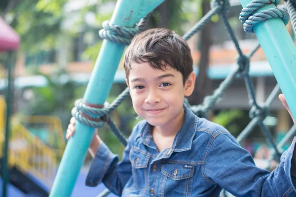 Liten pojke klättring på repet på lekplats — Stockfoto