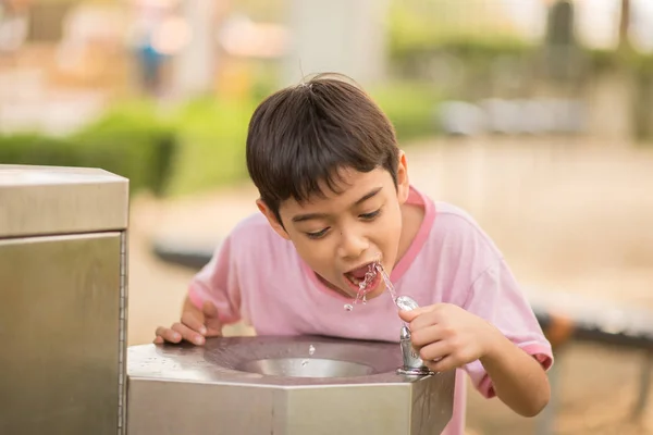 Küçük Asyalı çocuk içme suyu genel parkta — Stok fotoğraf