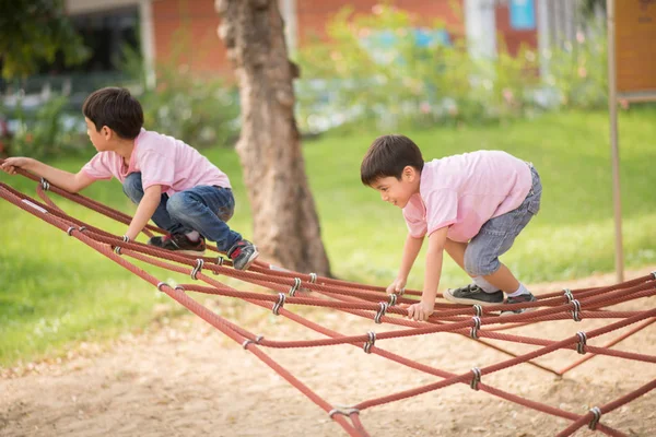 Piccolo asiatico ragazzo arrampicata su il corda in il parco — Foto Stock