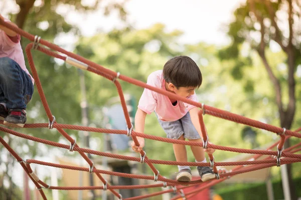 Piccolo asiatico ragazzo arrampicata su il corda in il parco — Foto Stock