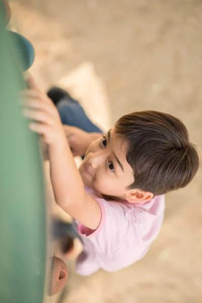 Pequeño chico asiático trepando en la roca en el parque — Foto de Stock