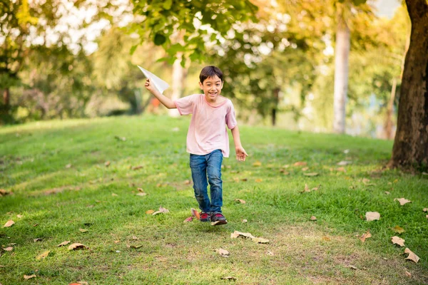 Liten asiatisk pojke spela planet papper i parken — Stockfoto