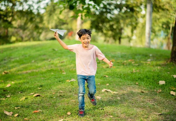 Liten asiatisk pojke spela planet papper i parken — Stockfoto