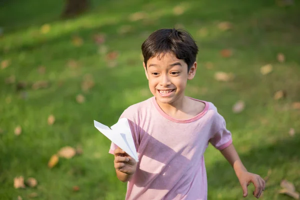 Маленький азиатский мальчик играет на бумаге в парке — стоковое фото