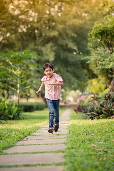 Маленький азиатский мальчик, бегающий вместе в парке с счастливым летним временем — стоковое фото
