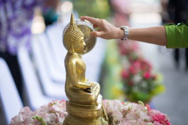 İnsanlar yavaşça gövde veya Buda heykeli ellerini su dökün. 