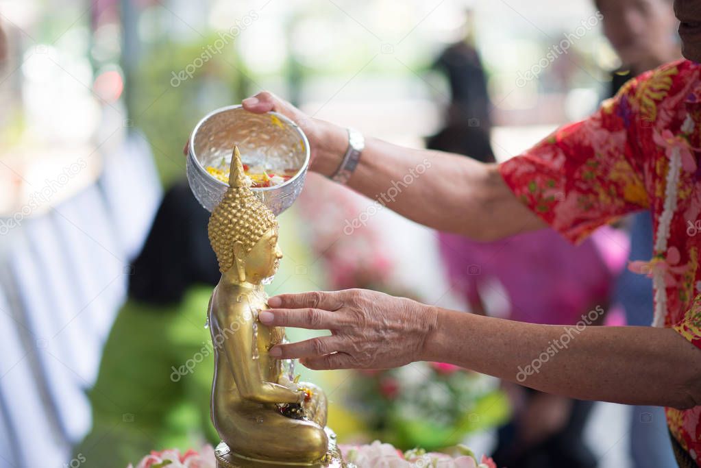 People gently pour the water on the torso or the hands of the Buddha statue. 