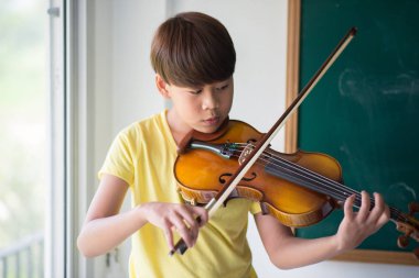 Küçük çocuklar oynamak ve müzik sınıfı odasında keman uygulama