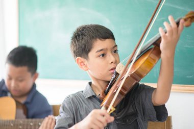 Küçük çocuklar oynamak ve müzik sınıfı odasında keman uygulama