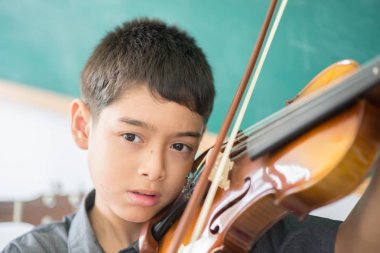 Küçük çocuklar oynamak ve müzik sınıfı odasında keman uygulama