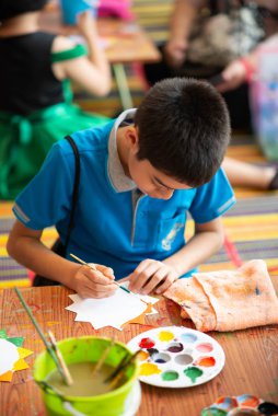 Young boy painting paper craft water color in the class 