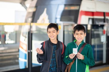 Küçük çocuk elektrikli bilet alıyor ve aile ile birlikte gökyüzü tren istasyonunda yürüyor. 