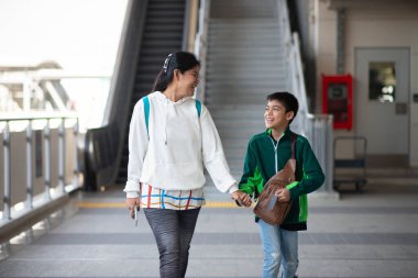 Küçük çocuk elektrikli bilet alıyor ve aile ile birlikte gökyüzü tren istasyonunda yürüyor. 