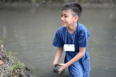 Çocuk boş ellerle balık tutuyor.
