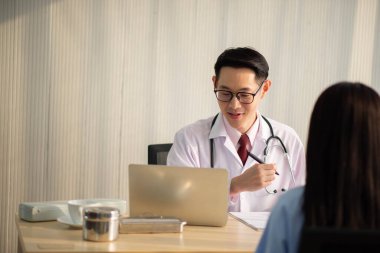 Asyalı doktor ve hasta hastanede sağlık sigortası hastalığını konuşuyor ve kontrol ediyor.