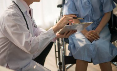 Asyalı doktor ve hasta hastanede sağlık sigortası hastalığını konuşuyor ve kontrol ediyor.