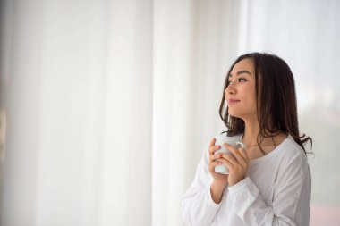 Asyalı kadın sabahları evde çalışıyor, kahve içiyor ve dinleniyor.