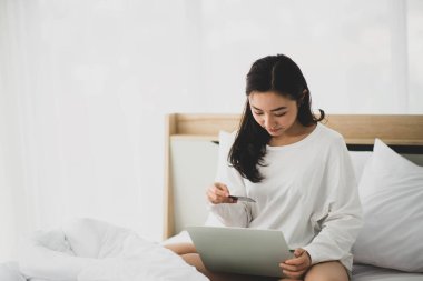 Asyalı kadın evden internet üzerinden defter ve alışveriş yapıyor. 