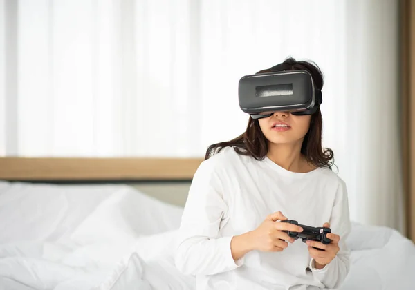 Asian woman playing vr 3d game in the bed at bedroom