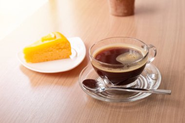 Ahşap masa üzerinde siyah kahve ve turuncu kek