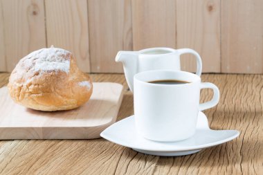 Kahve fincanı ve Maya ahşap masa üzerinde rulo