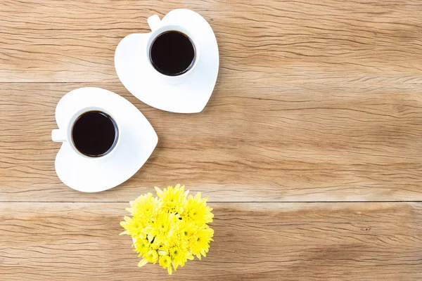 Koffie kopjes en schoteltjes van de hartvormige op houten achtergrond — Stockfoto