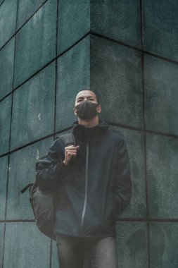 Gerçek bir anti-kirlilik, anti-kirlilik ve virüsler takan adam yüz maskesi; havada yoğun duman ve büyük bir torba tutuyor