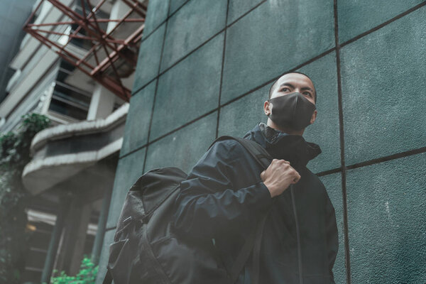 Man wearing a real anti-pollution, anti-smog and viruses face mask; dense smog in air and holding big bags