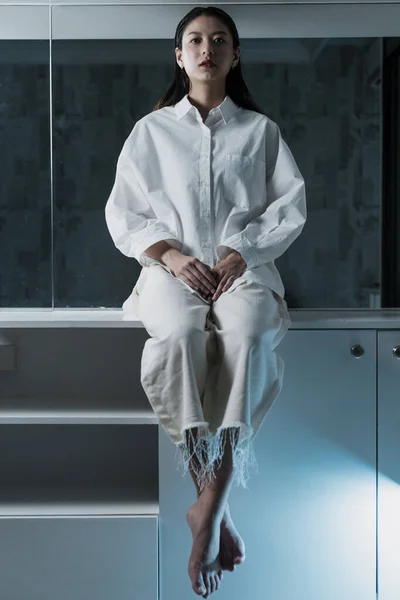 Nero Capelli Lunghi Donna Vestiti Bianchi Sedersi Sul Mobile Bianco — Foto Stock