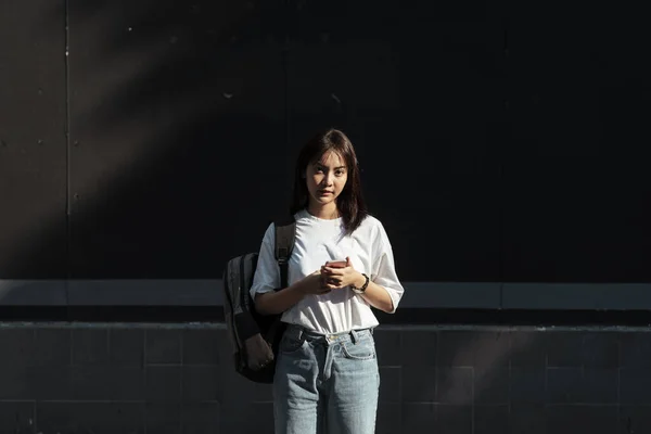 Tailandês Menina Frente Parede Segurando Smartphone Olhando Diretamente Para Câmera — Fotografia de Stock