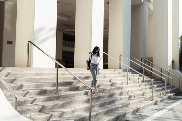 College girl walking down the stair after she finish her reading at the library.